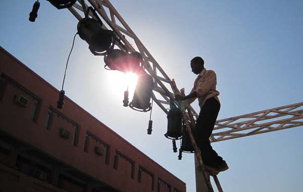 The Future University technician installing stage lighting under the hot sun